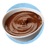 Primer plano de un tazón blanco pequeño con salsa de chocolate sobre un fondo azul.