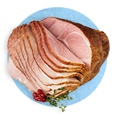 Close up of a baked ham sliced half way through, on a blue background.