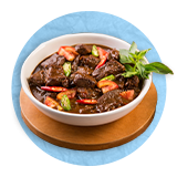 Close up of beef stew in a white bowl on a round cutting board, on a blue background.