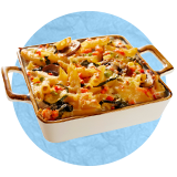 Primer plano de una fuente de horno blanca con asas de cobre con una cazuela de desayuno sobre un fondo azul.