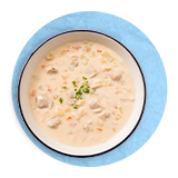 Plano aéreo de un tazón con bisqué de langosta sobre un fondo azul.