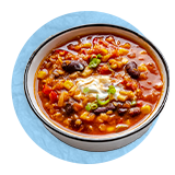 Plano aéreo un tazón blanco con sopa de chili de frijoles sobre un fondo azul.