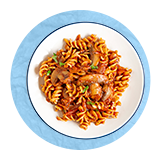 Plano aéreo de un plato blanco con pasta fusilli en salsa de tomate sobre un fondo azul.