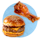 Primer plano de una hamburguesa de queso en un pan con sésamo junto a una rebanada de tocino sobre un fondo azul.