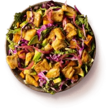 Overhead of a bowl of plant-based chik'n on top of a mixed green salad.