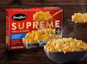 Tazón humeante de caracolitos con queso frente a una caja roja Stouffer's con la SUPREME en letras doradas en el centro.