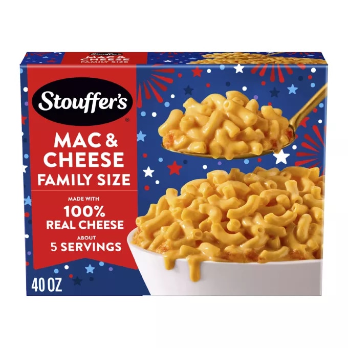 Caja de Macaroni & Cheese con un plato y una fuente de macarrones con queso sobre una mesa cerca del nombre del producto y de una etiqueta que dice "Queso 100% auténtico".