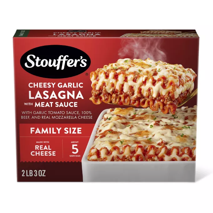 Caja de Cheesy Garlic Lasagna with Meat Sauce con un plato y una fuente de lasaña debajo del nombre del producto y el logo de STOUFFER'S.