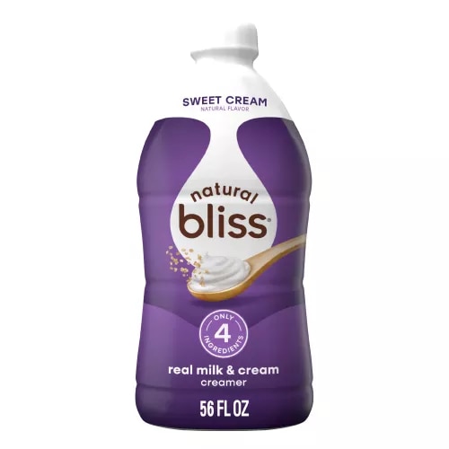 Large white bottle of natural bliss Sweet Cream flavored Creamer with a purple label above a spoon of sugar and swirl of milk