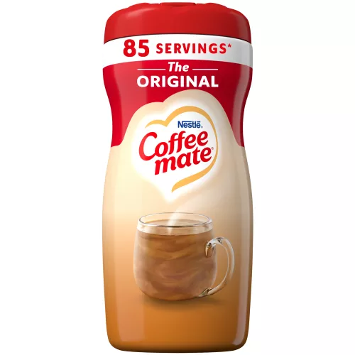 Una lata de creamer en polvo Original con una tapa roja y una etiqueta roja encima de una taza y un biscotti.