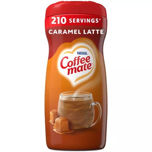 Una lata marrón de creamer Coffee mate Caramel Latte con una etiqueta roja encima de una taza de café con gotas de caramelo.