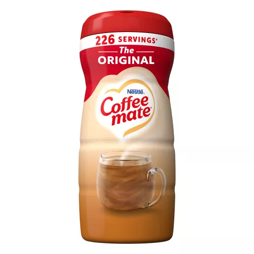 Una lata de creamer en polvo Coffee mate Original con una tapa roja y una etiqueta roja encima de una taza de café y un biscotti.