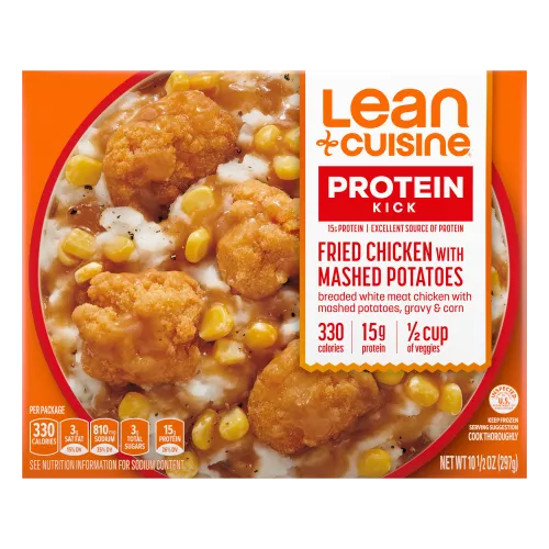 A box of oven fried chicken with mashed potatoes with Protein Kick label with 300 calories, 14 grams of protein and half cup of veggies near a bowl of corn, chicken and potatoes.