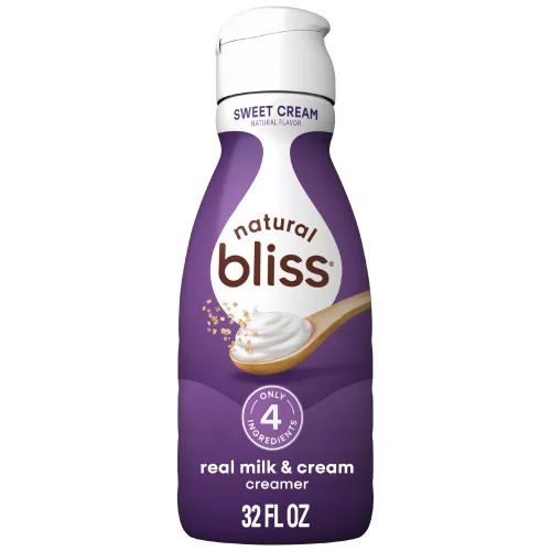 White bottle of natural bliss Sweet Cream flavored Creamer with a purple label above a spoon of sugar and swirl of milk.