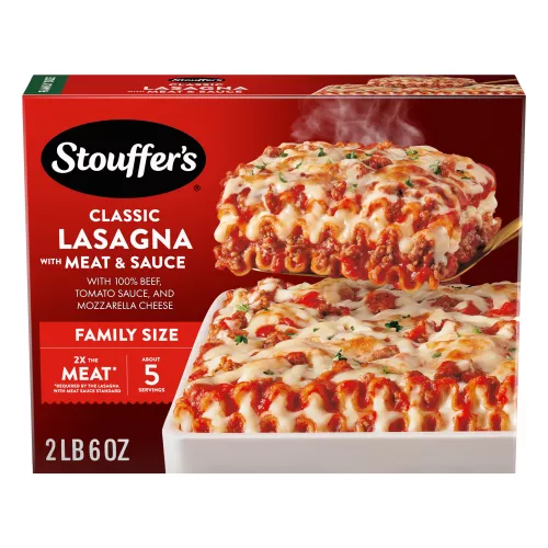 A plate of Lasagna with Meat & Sauce beside a red dish of lasagna on a table below the product name and "2x the Meat" label.