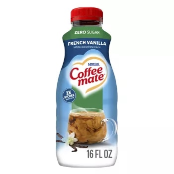 Una botella azul de creamer Zero Sugar French Vanilla que lee sin azúcar sobre una taza de café y granos de vainilla.