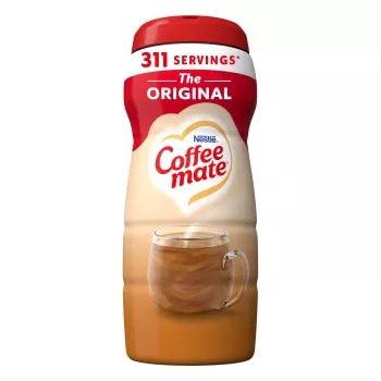Una lata de creamer Coffee mate Original con una etiqueta roja, una taza de café, un biscotti y el logotipo de Coffee mate.