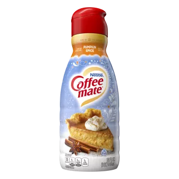 A bottle of Pumpkin Spice creamer with an orange label above a slice of pumpkin pie and cinnamon sticks.