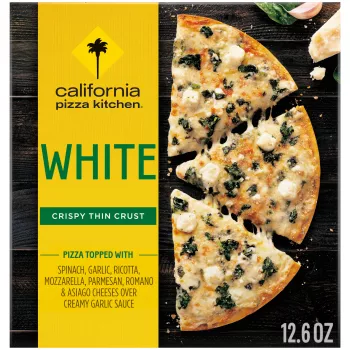 Box of White Pizza with half a pizza, garlic clove, basil, and parmesan on a black wooden surface.