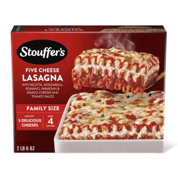 Caja de Cheese Lovers Lasagna con un plato de lasaña y una fuente roja sobre una mesa con el nombre del producto y una etiqueta que dice "50% más queso".