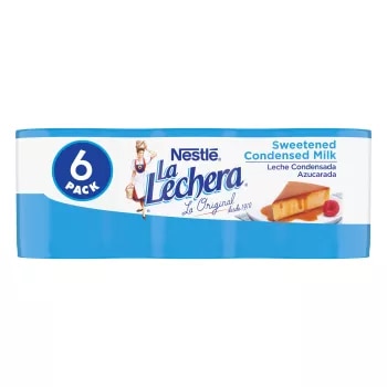 Seis latas envueltas en plástico de la leche condensada azucarada La Lechera presentan el logo y una imagen de una lata en la envoltura de plástico.