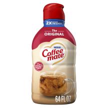 Una botella de creamer Coffee mate Original con una tapa roja y una etiqueta roja encima de una taza de café y un biscotti.