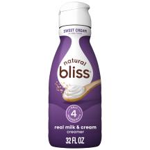 White bottle of natural bliss Sweet Cream flavored Creamer with a purple label above a spoon of sugar and swirl of milk.