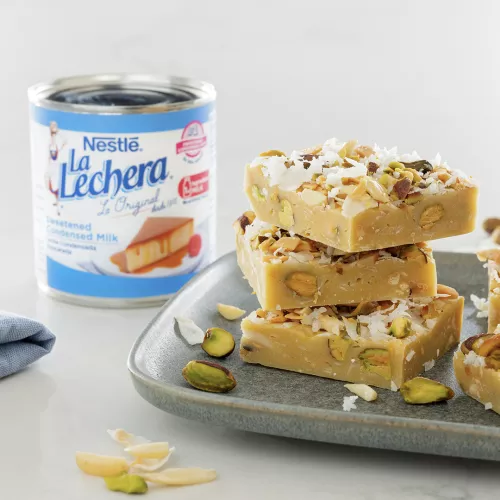 Photograph: stacked pistachio-coconut fudge squares on plate beside La Lechera can