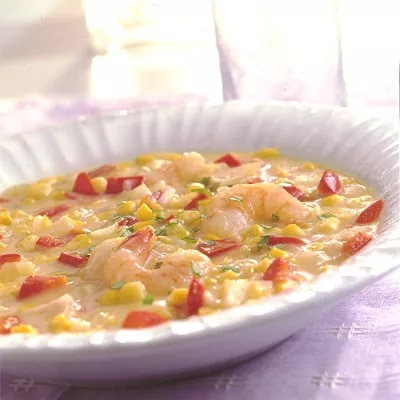 Fotografía de sopa cremosa con camarones, maíz y pimiento rojo en plato blanco