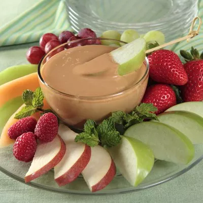 Photograph: fruit platter with glass bowl of caramel dip, apple slices, strawberries, grapes, mint.