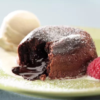 Fotografía de volcán de chocolate abierto con helado de vainilla y frambuesa