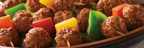 Fotografía de brochetas de albóndigas y pimientos multicolores sobre plato