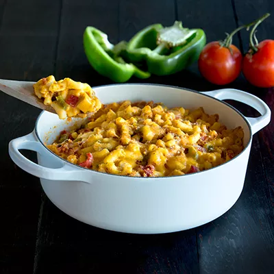 Fotografía de cazuela blanca con macarrones gratinados, pimiento verde y tomates