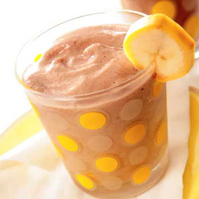 Fotografía: batido de chocolate y plátano en vaso con lunares amarillos, rodaja de plátano