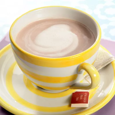 Fotografía: taza a rayas amarillas con chocolate caliente, espuma en remolino y etiqueta roja