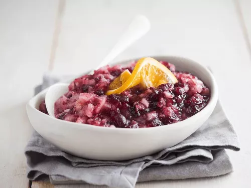 Fotografía de salsa casera de arándanos con tiras de naranja en bol blanco
