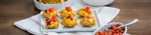 Fotografía: canapés de totopos con pico de gallo y guacamole, salsa en cuchara y bol de chips