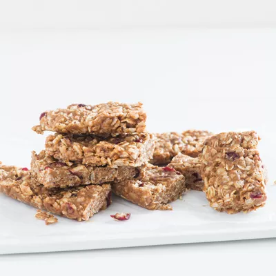 Fotografía de barras de granola con avena y frutos secos, apiladas sobre plato blanco