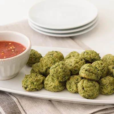 Fotografía: bolitas verdes tipo falafel en plato blanco con salsa roja