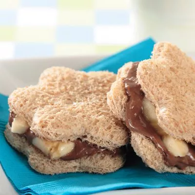 Fotografía: sándwiches en forma de corazón con chocolate y plátano sobre servilleta azul.