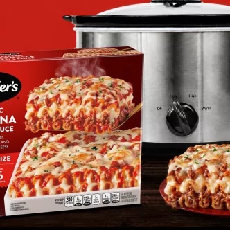 Photograph of two boxed frozen lasagnas, a baked lasagna and stainless slow cooker on red.