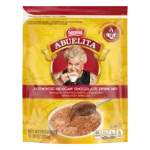 A yellow pouch with red labels and a spoon stirring hot chocolate mix into a yellow mug below the Abuelita logo.