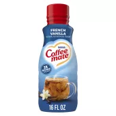 Una botella azul de creamer Coffee mate French Vanilla con una tapa roja y una etiqueta azul sobre una taza de café y vainas de vainilla.