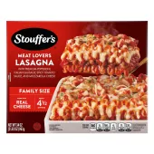 Caja de Meat Lovers Lasagna con un plato de lasaña cerca de un plato, el nombre del producto, el logo de STOUFFER'S y una etiqueta que dice "TAMAÑO FAMILIAR".
