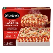A plate of Lasagna with Meat & Sauce beside a red dish of lasagna on a table below the product name and "2x the Meat" label.