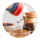 Polvo que se vacía desde una lata en una taza de café cerca de una cafetera que está sirviendo.