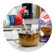 Creamer pours from a bottle into a mug of coffee on a counter near another bottle of creamer.